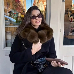 Elegant black wool coat with a large brown faux fur collar in a street style setting