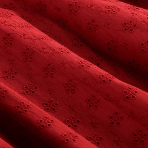 Macro shot of dark red fabric with intricate floral embroidery and eyelet details