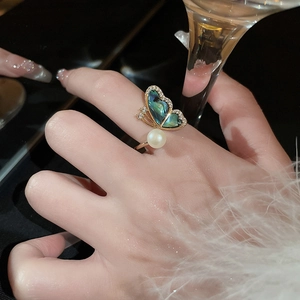 Detailed shot of gold butterfly ring with abalone shell and pearl on model's finger