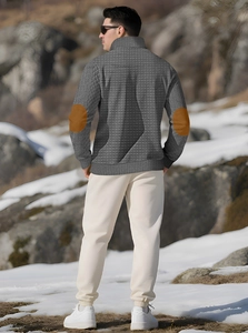 Detail of grey waffle-knit jacket with brown elbow patches on a model in a winter landscape