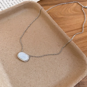 Detailed shot of silver resin oval pendant necklace on vintage paper background