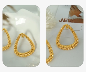 Detailed view of large golden triangular hoop earrings with textured twist design