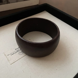Close-up detail of smooth matte dark brown wide wooden resin bangle for women