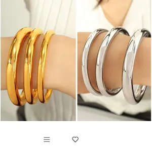 Close-up of chunky minimalist 18K gold and silver plated bangles with mirror finish