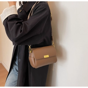 Sac bandoulière en cuir marron avec sangle tissée et boucle dorée sur modèle