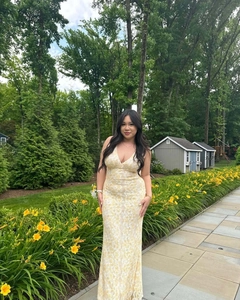 Detailed close-up of yellow lace V-neck evening dress in a lush outdoor garden setting