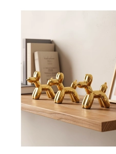 Dettaglio di tre sculture a forma di cane palloncino dorato con finitura a specchio su scaffale