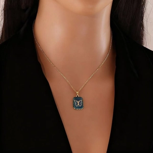 Collier doré avec pendentif papillon bleu carré sur cou de mannequin et col noir