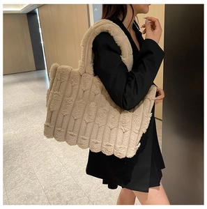 Plush beige tote bag with textured stripes shown from a side view on a model