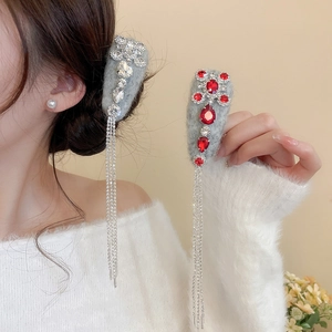 Detail view of rhinestone drop tassels on a grey flocked hair clip with red gemstones