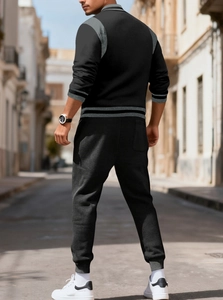Detailed view of black tracksuit set with grey striped cuffs on a city street background