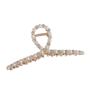 Grande pince à cheveux dorée avec perles et strass sur un fond blanc neutre