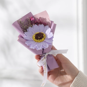 Detail of purple artificial sunflower bouquet with romantic paper wrap and ribbon