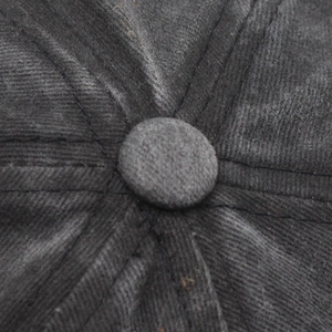 Macro detail of dark grey corduroy baseball cap top button and six-panel stitching structure