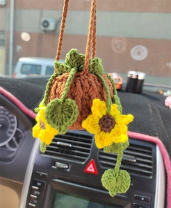 Close-up of a handmade knitted sunflower car hanging basket with green leaves detail