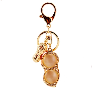 Golden peanut keychain with sparkling rhinestones and cat eye stones on a white background