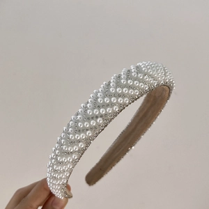 Detailed view of padded headband featuring wave patterns of white pearls and sparkling rhinestones