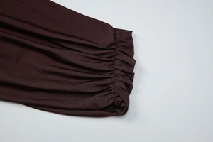 Détail rapproché d'une robe marron foncé avec poignets froncés et texture de tricot fin
