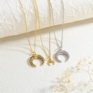 Macro shot of gold and silver horn necklaces with colorful cubic zirconia on white paper