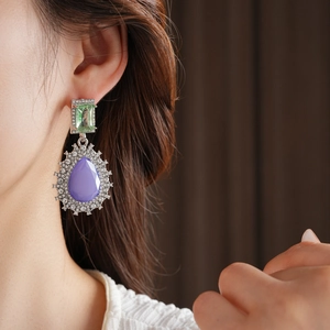 Gros plan de boucles d'oreilles vintage avec cristal rectangle vert et goutte violette