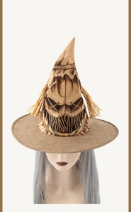 Close-up of burlap scarecrow witch hat with black facial print and straw details