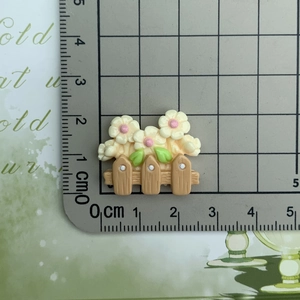 Close-up of resin flower fence charm on a centimeter scale ruler for size measurement