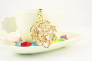 Detailed shot of pink enamel rose keychain with rhinestones hanging on a ceramic cup