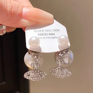Macro detail of silver orb earrings with sparkling crystals and white pearls