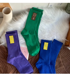 Détail de chaussettes en coton colorées vert, violet et bleu avec étiquette sourire