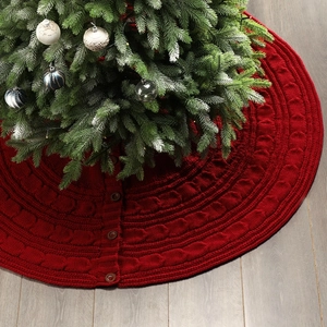 Detail of red cable knit Christmas tree skirt with three vintage buttons on wood floor