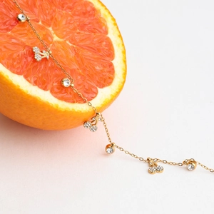 Collana in acciaio al titanio con ciondoli a ciliegia scintillanti su agrumi freschi