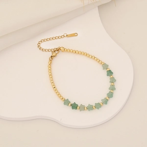 Detailed view of handmade beaded bracelet with gold beads and green star pendants