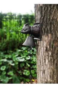 Close-up of vintage cast iron cat-head doorbell mounted on a rustic tree trunk