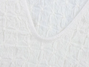 Detailed close-up of white smocked seersucker fabric texture and professional hem stitching