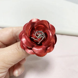 Macro shot of detailed red metallic camellia flower brooch with layered petals