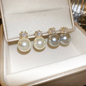 Détail de boucles d'oreilles en zircon et perles blanc et gris dans une boîte en velours