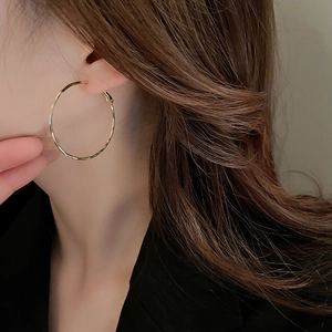 Detailed view of large gold hoop earrings worn by a model for a modern fashion look