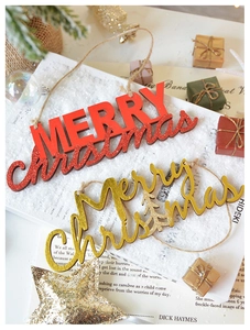 Close-up of wooden Merry Christmas hanging ornaments with gold foil lettering on snow