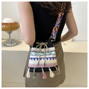 Ethnic embroidered bucket bag with colorful tassels and woven shoulder strap on model