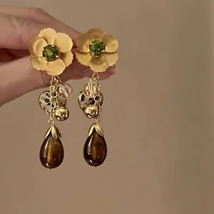 Makroaufnahme von Vintage-Ohrhängern mit Blumenmuster, grünen Steinen und Edelsteinen