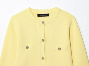 Detail of light yellow knit cardigan featuring textured golden buttons and faux pockets