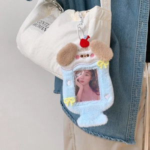 Detail of light blue puppy plush photo card holder with cherry charm hanging on a bag