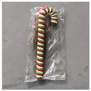 Detail of candy cane ornament with red and white knit stripes and burlap bow decoration