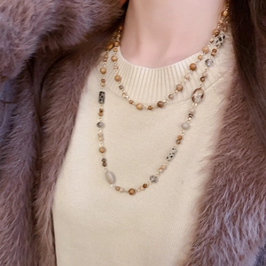 Close-up of a double-layered gold-plated beaded necklace with earth-toned stones