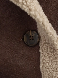 Close-up of marble pattern button on dark brown suede and white sherpa lining