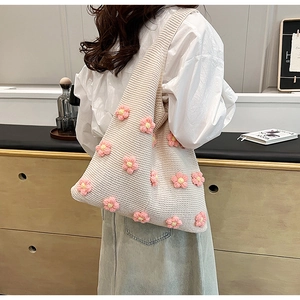 Detailed view of beige knitted tote bag featuring pink and yellow floral embroidery