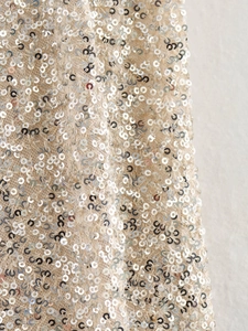 Macro shot of silver sequins on knitted fabric showing metallic texture and details