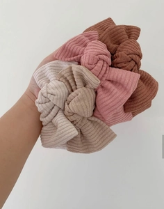 Detail of four ribbed knit bow baby headbands in beige, camel, mauve and brown tones