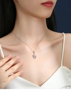 Close-up of S925 sterling silver hollow heart pendant with sparkling moissanite on a model