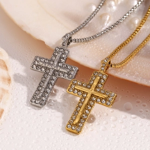 Detail of gold and silver cross necklaces with rhinestones on a wet water surface
